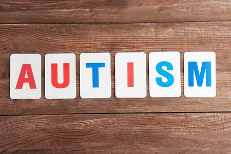 Word Autism on wooden background