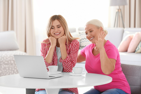 Young woman using laptop with elderly mother at homeの写真素材