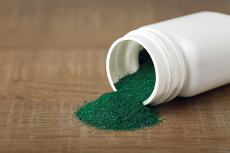 Spirulina powder and white container on tableの写真素材