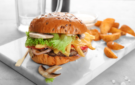 Board with fresh tasty burger on tableの写真素材