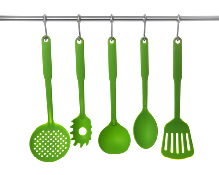Set of cooking utensils hanging on rack, isolated on whiteの写真素材
