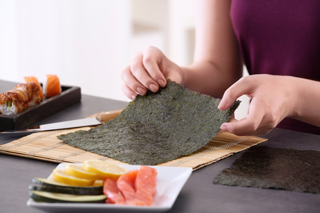 Young woman making sushi rolls at homeの写真素材