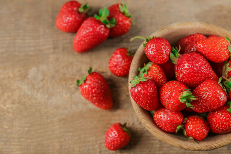 Bowl with fresh strawberries on wooden tableの写真素材