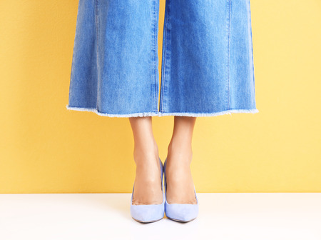 Young woman in stylish shoes against color wallの写真素材