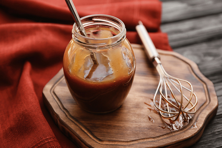 Jar with tasty caramel sauce on wooden boardの写真素材