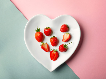 Heart shaped plate with strawberries on color backgroundの写真素材