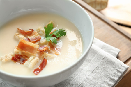 Bowl of yummy potato soup with bacon on wooden tableの写真素材
