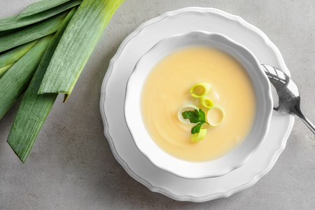 Bowl of yummy potato soup with leek on tableの写真素材