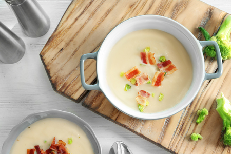 Saucepan of yummy potato soup with bacon on wooden boardの写真素材