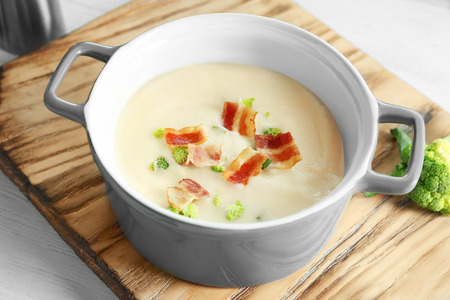 Saucepan of yummy potato soup with bacon on wooden boardの写真素材