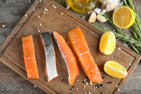 Slices of salmon fillet and ingredients for marinade on tableの写真素材