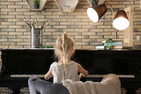 Little girl playing piano indoorsの写真素材