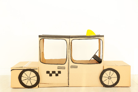 Cardboard taxi on white wall backgroundの写真素材