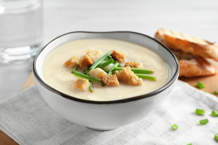 Bowl of yummy potato soup with leek on tableの写真素材