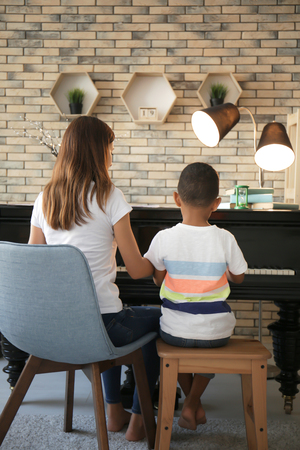 African-American boy with teacher learning to play piano indoorsの写真素材