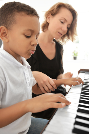 African-American boy with teacher learning to play piano indoorsの写真素材
