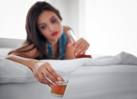Young woman drinking alcohol at homeの写真素材
