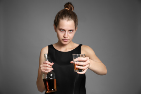 Young woman drinking alcohol on color backgroundの写真素材
