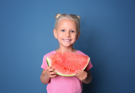 Cute girl eating watermelon on color backgroundの写真素材