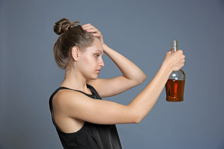 Young woman drinking alcohol on color backgroundの写真素材