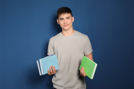 Teenage boy with books on color backgroundの写真素材