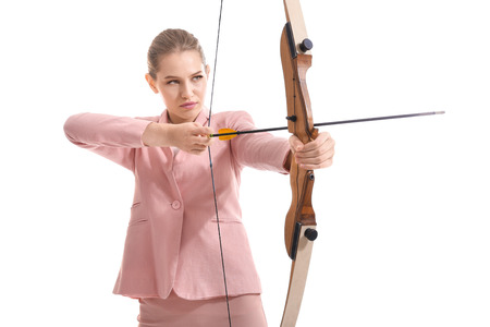 Young woman in formal clothes practicing archery on white background