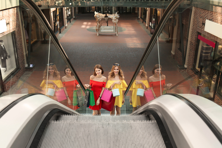 Beautiful women with shopping bags on escalator at strip mallの写真素材