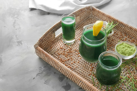 Glasses of wheat grass juice on wicker trayの写真素材