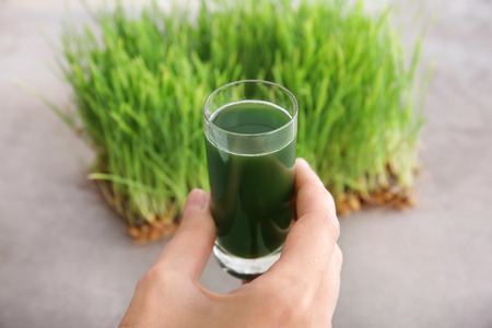 Woman holding shot of wheat grass juice, close upの写真素材