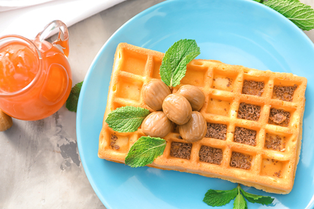 Plate with tasty waffle and caramel candies on tableの写真素材