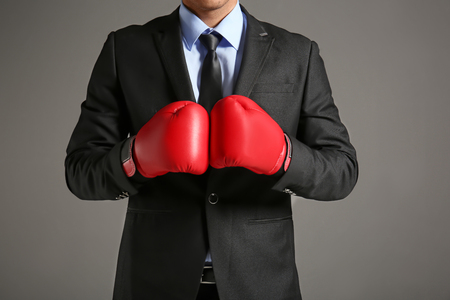 Businessman in boxing gloves on grey backgroundの写真素材