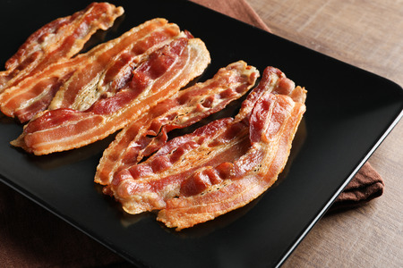 Plate with cooked bacon rashers on table, closeupの写真素材