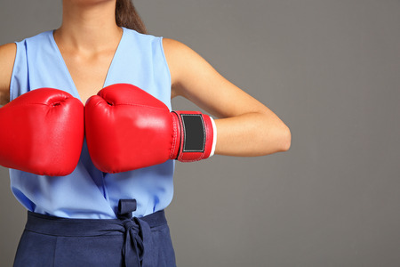Businesswoman in boxing gloves on grey backgroundの写真素材
