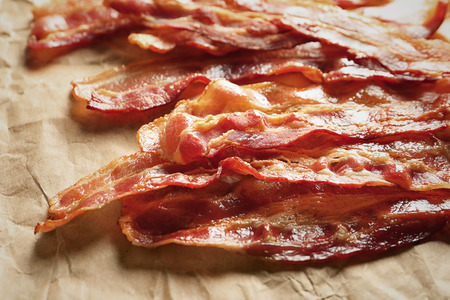 Cooked bacon rashers on parchment, closeup