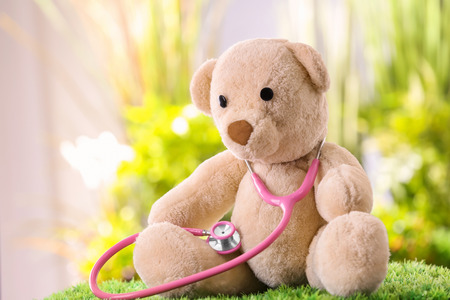 Cute teddy bear with stethoscope on blurred background. Child's doctor conceptの写真素材