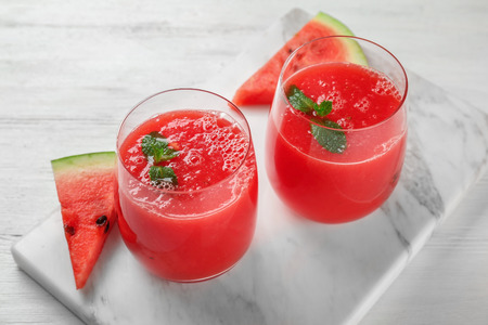 Marble board with glasses of fresh watermelon smoothie on white tableの写真素材