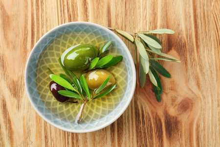Bowl with canned olives on wooden backgroundの写真素材