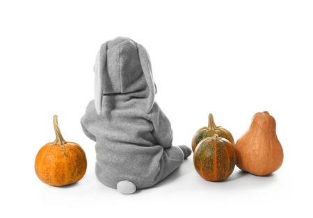 Adorable baby in bunny costume with pumpkins on white backgroundの写真素材