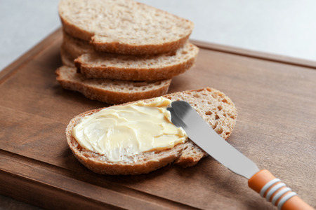 Slice of bread with butter on wooden boardの写真素材