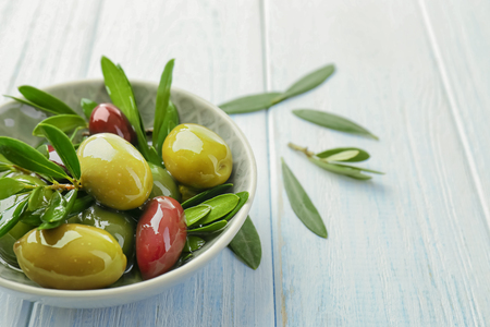 Bowl with canned olives on white wooden backgroundの写真素材