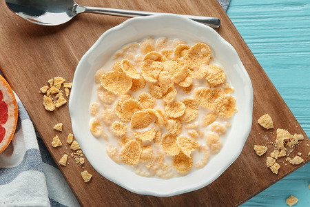 Plate with cornflakes and milk on wooden boardの写真素材