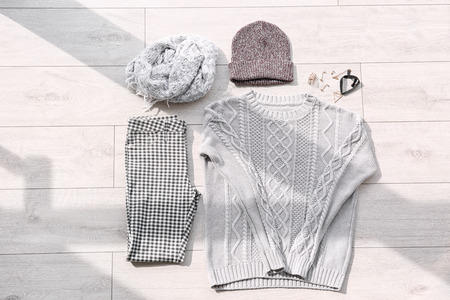 Set of stylish female clothes and accessories on wooden floor