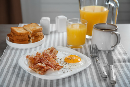 Plate with fried egg and bacon on tableの写真素材