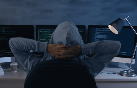Man wearing hoodie hacking server in dark room