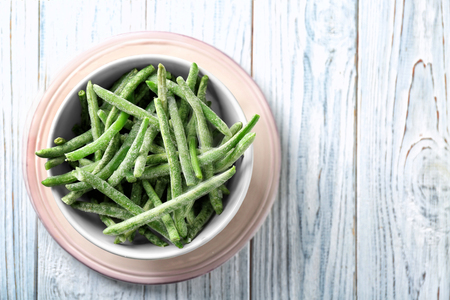 Bowl with frozen green beans on wooden backgroundの写真素材