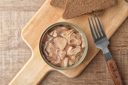 Open tin can with fish and bread on wooden backgroundの写真素材