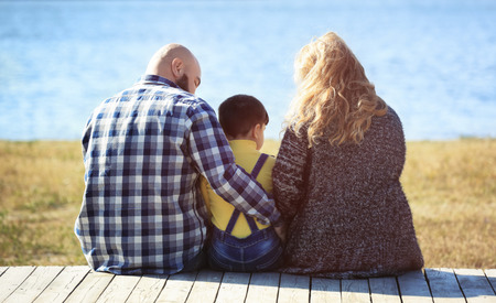 Overweight couple with son near river on sunny dayの写真素材