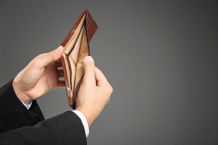 Hands of young businessman with empty purse on grey backgroundの写真素材