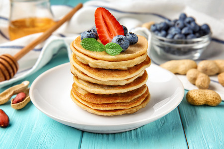 Plate with buckwheat pancakes and berries on wooden tableの写真素材