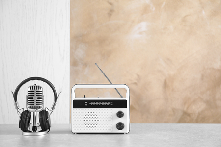 Retro radio, headphones and microphone on table against light wallの写真素材